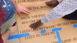 Artists use a stencil to install a temporary poem on the sidewalk in Boston.